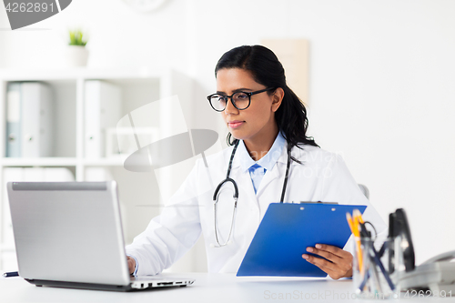 Image of doctor with laptop and clipboard at hospital