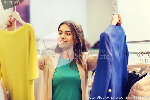 Image of happy young woman choosing clothes in mall