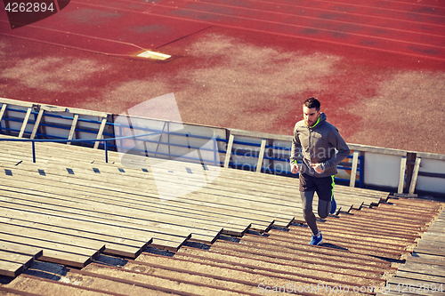 Image of happy young man running upstairs on stadium