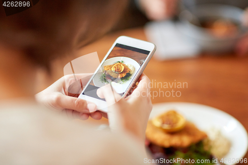 Image of woman with smartphone photographing food at cafe