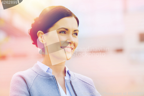 Image of young smiling businesswoman over office building