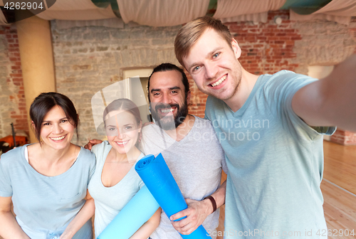 Image of happy friends at yoga studio or gym taking selfie
