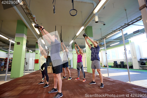 Image of group of people with kettlebells exercising in gym