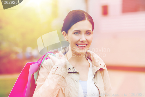 Image of smiling woman with shopping bags coming from sale