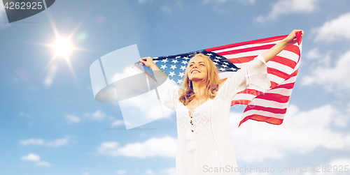 Image of happy young woman with american flag over blue sky