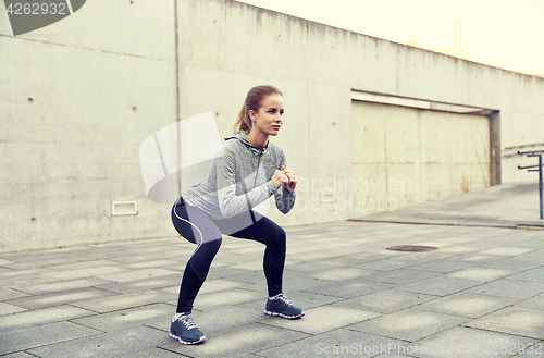 Image of happy woman doing squats and exercising outdoors