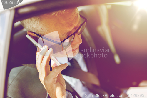 Image of senior businessman calling on smartphone in car