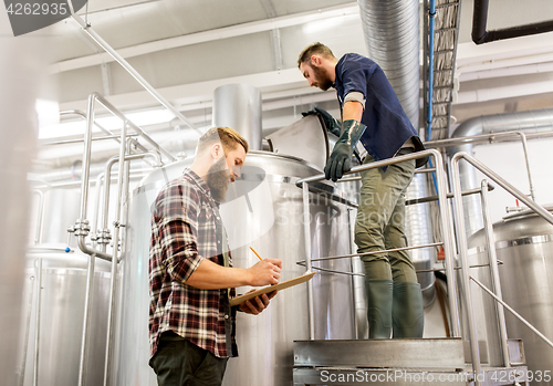 Image of men with clipboard at craft brewery or beer plant