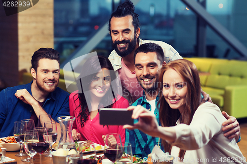 Image of friends taking selfie by smartphone at restaurant