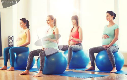 Image of happy pregnant women exercising on fitball in gym