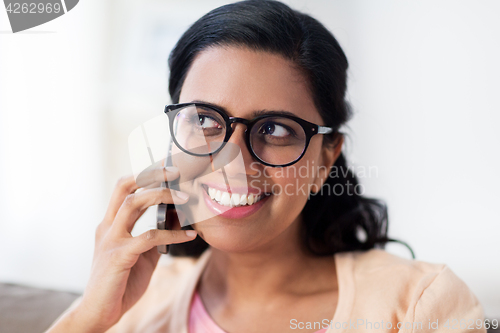 Image of happy indian woman calling on smartphone at home