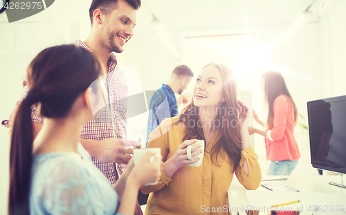 Image of happy creative team drinking coffee at office