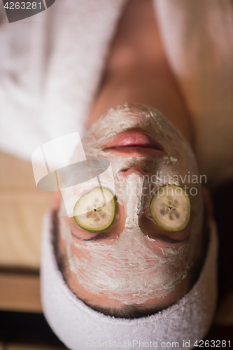 Image of woman is getting facial clay mask at spa