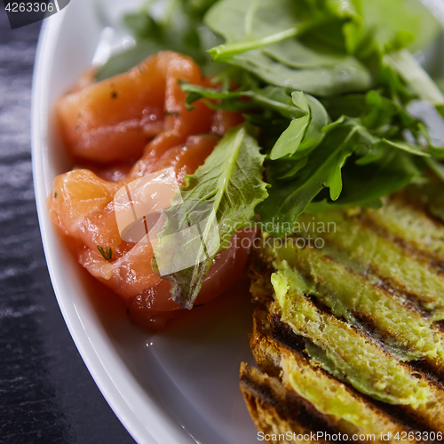 Image of sandwich with smoked salmon, cheese, tomatoes and herbs for healthy breakfast. close up