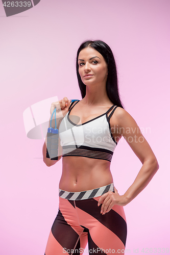 Image of The woman training against pink studio with jump rope