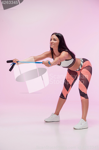 Image of The woman training against pink studio with jump rope