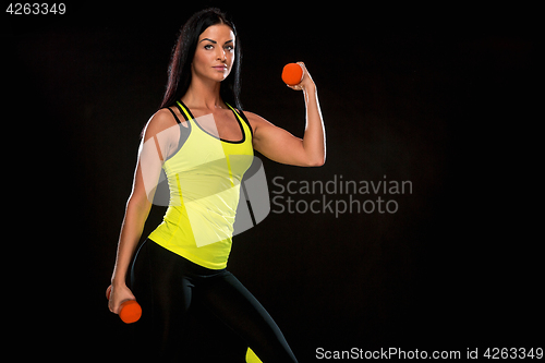 Image of The woman training against black studio with red dumbbells