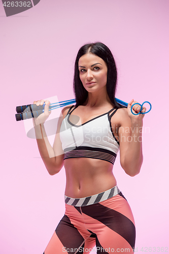 Image of The woman training against pink studio with jump rope