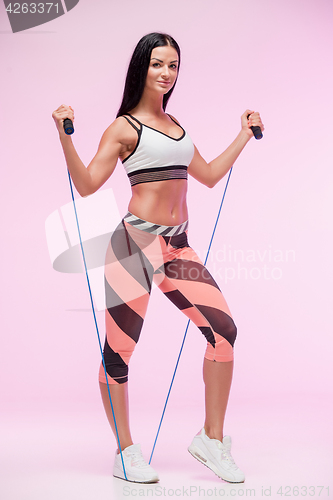 Image of The woman training against pink studio with jump rope