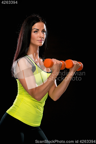 Image of The woman training against black studio with red dumbbells