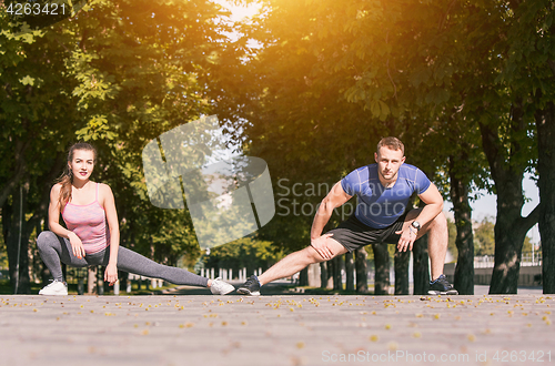 Image of Fit fitness woman and man doing stretching exercises outdoors at park