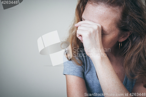 Image of one sad woman sitting near a wall