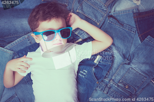 Image of Cute little boy with sunglasses on the background jeans.