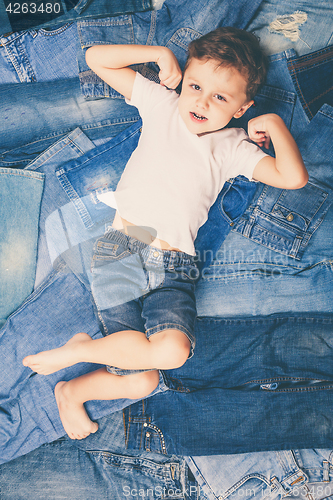 Image of Cute little boy with sunglasses on the background jeans.