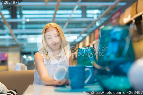 Image of Woman choosing the right decor for her apartment in a modern home furnishings store.