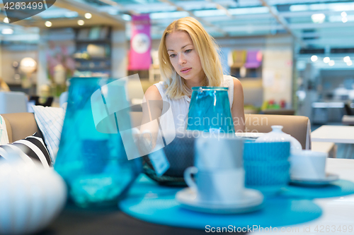 Image of Woman choosing the right decor for her apartment in a modern home furnishings store.