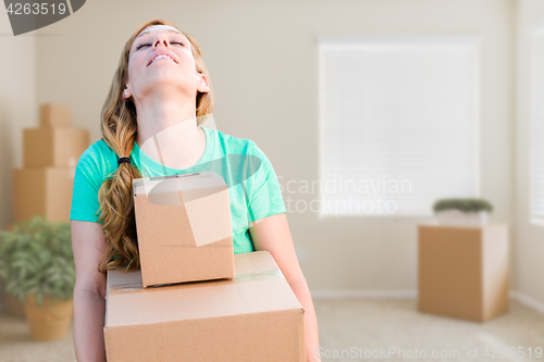 Image of Tired Young Adult Woman Holding Moving Boxes In Empty Room In A 