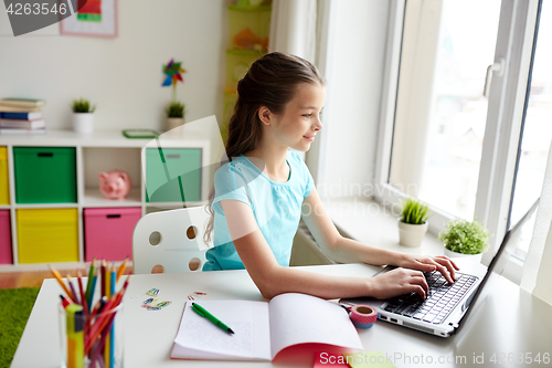 Image of happy girl typing on laptop at home
