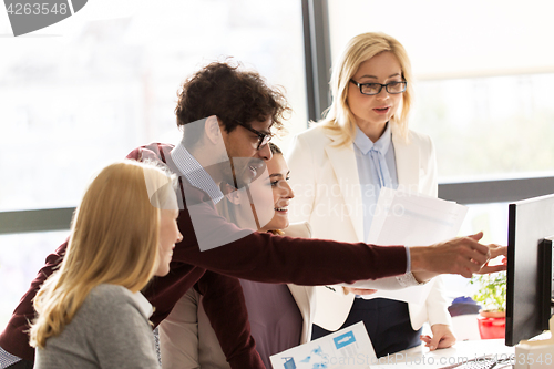 Image of happy creative team with computer in office