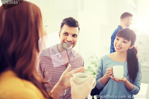 Image of happy creative team drinking coffee at office
