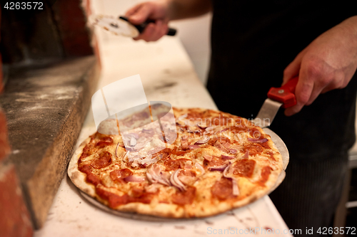 Image of cook with pizza peel and cutter at pizzeria