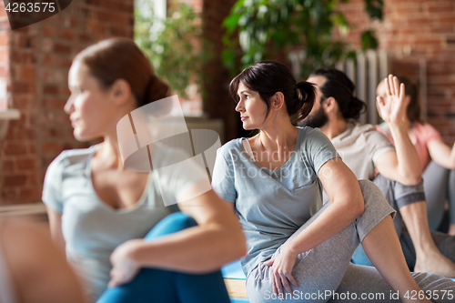 Image of group of people doing yoga exercises at studio