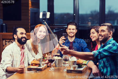 Image of friends taking selfie by smartphone at restaurant