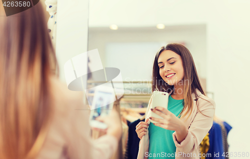 Image of woman taking mirror selfie by smartphone at store