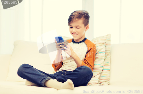 Image of boy with smartphone texting or playing at home