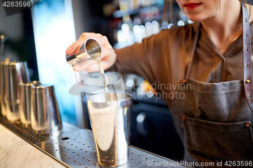 Image of bartender with cocktail shaker and jigger at bar
