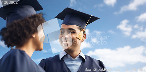 Image of happy students or bachelors over blue sky