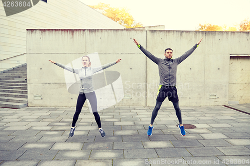 Image of happy man and woman jumping outdoors