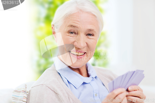 Image of happy senior woman playing cards at home