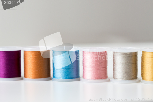 Image of row of colorful thread spools on table