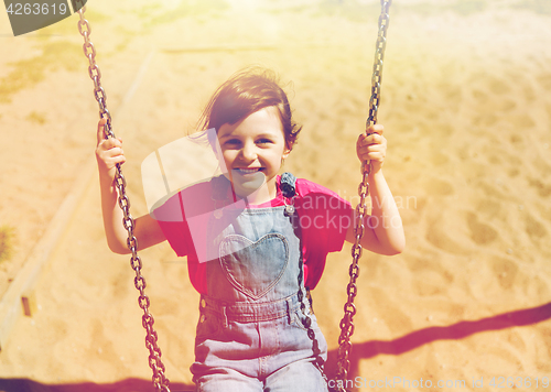 Image of happy little girl swinging on swing at playground