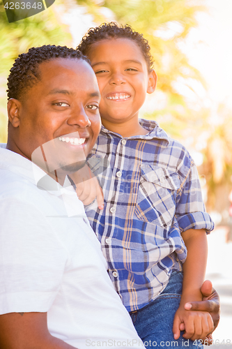 Image of Mixed Race Son and African American Father Playing Outdoors Toge