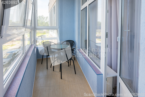 Image of A table and three chairs on the balcony in the apartment of a multistory apartment building