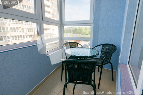 Image of A table and three chairs on the balcony in the apartment of a multistory apartment building