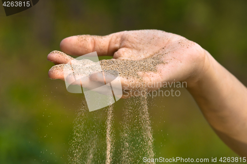 Image of sand running through hand like time running out