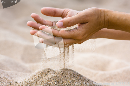 Image of sand running through fingers of woman